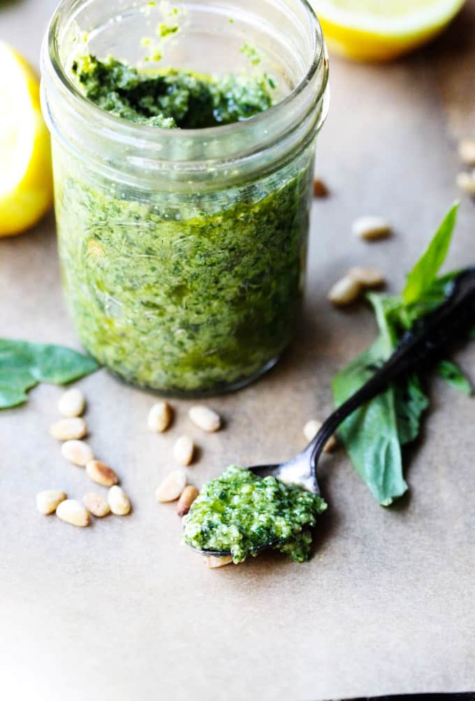 Basil pesto sauce on a spoon with jar on a side