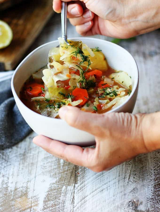 Holding a bowl and spoon of Slow Cooker Cabbage Soup