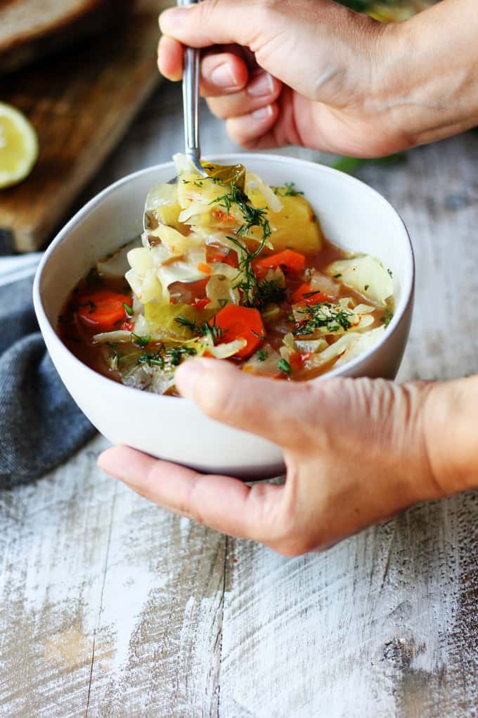 Holding a bowl and spoon of Slow Cooker Cabbage Soup 