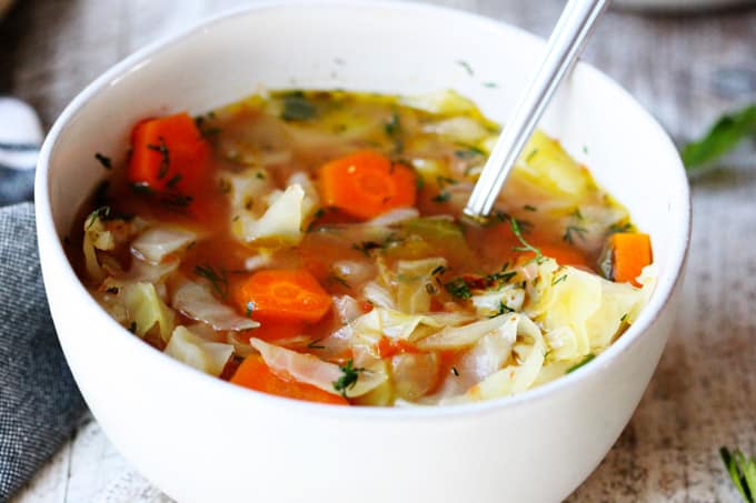 Slow cooker cabbage soup in a white bowl with spoon