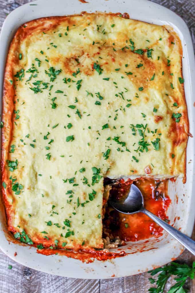 Overhead shot of vegetarian moussaka in casserole dish with spoon