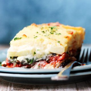 Horizontal shot of a vegetarian moussaka on a blue plate with fork