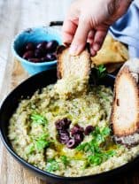 Melitzanosalata - Greek Eggplant Dip in a bowl with hand bread dipped in it