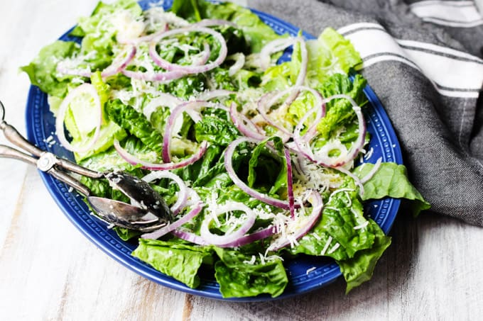 Simple green salad on serving blue plate with kitchen towel on a side