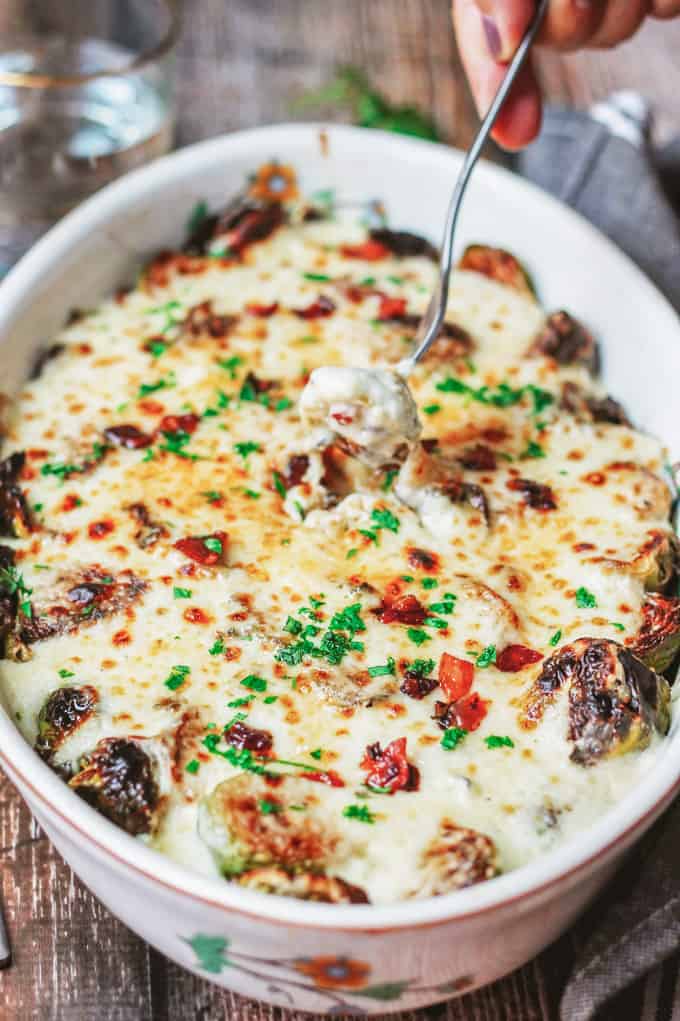 Cheesy Brussels Sprouts au gratin in a baking dish with fork