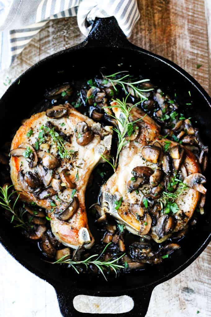 Mushroom pork chops with garlic butter and herbs in a skillet