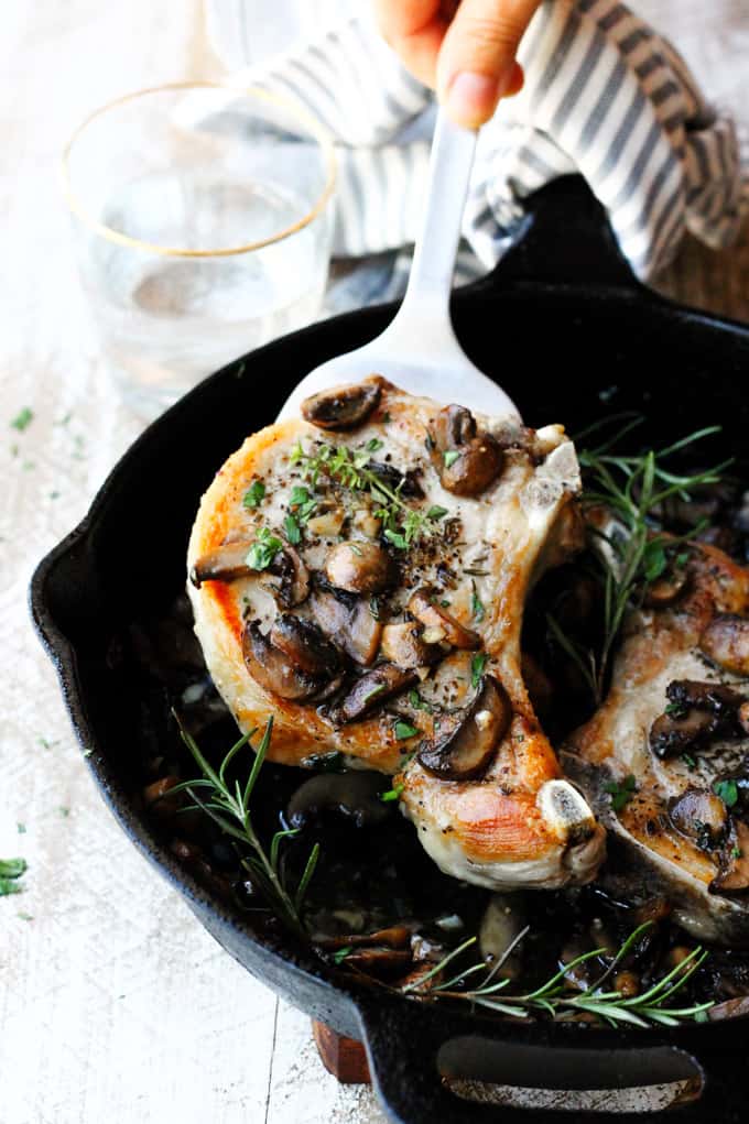 Picking up pork chops with mushrooms from the skillet