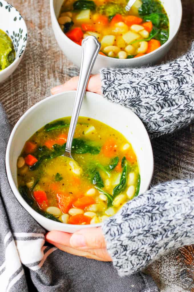 Serving Instant Pot Bean Soup with Spinach and Pesto in a bowl with a spoon