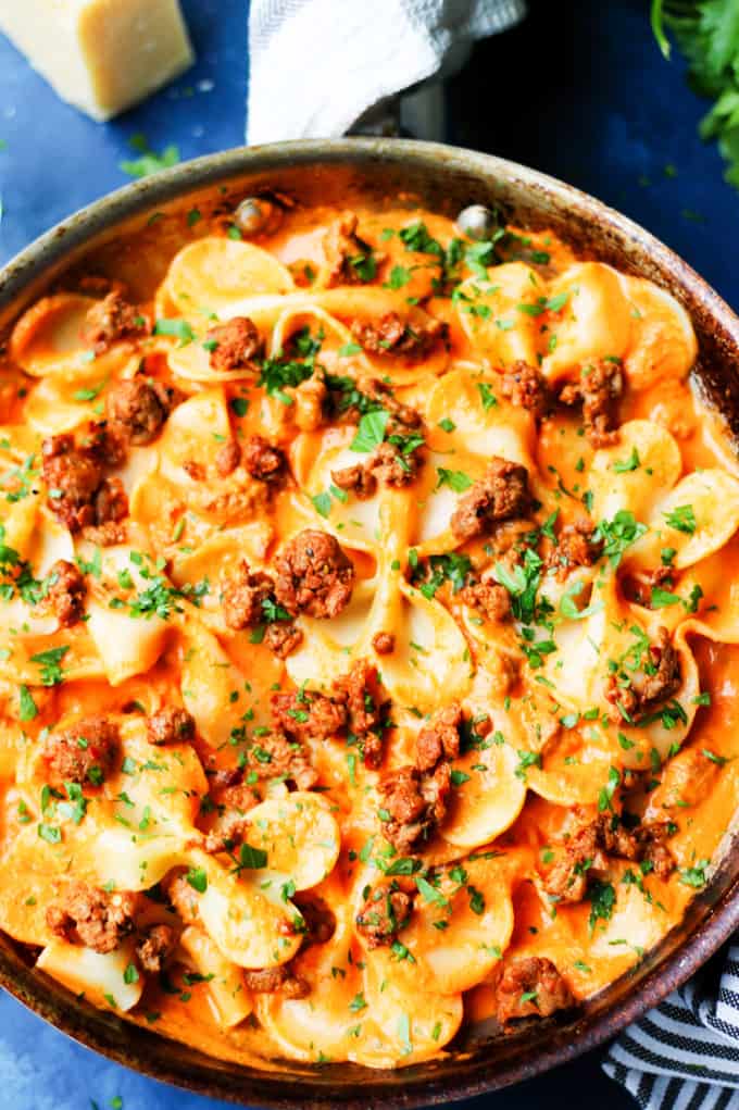 Pasta in Vodka Sauce with Italian sausage in a skillet on a blue backround