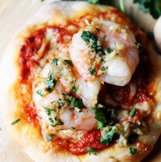 Pizzette with Garlic Shrimp and Roasted Pepper Pesto on a pizza peel