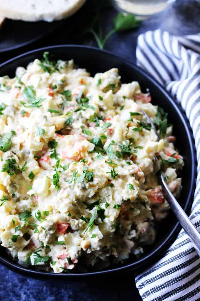 Russian Salad in a bowl with spoon and kitchen towel on a side