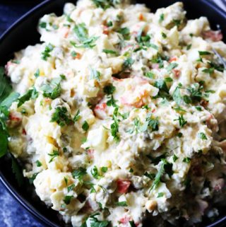 Russian potato salad in a bowl with spoon and forks on a side