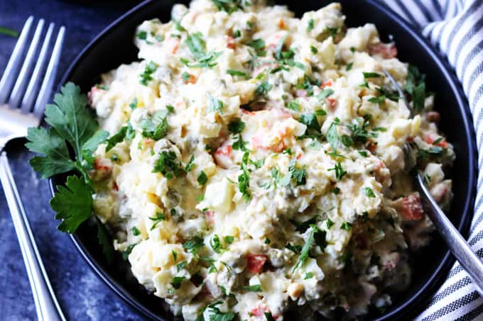 Russian potato salad in a bowl with spoon and forks on a side