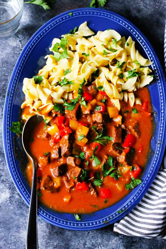 Hungarian Goulash on a blue plate with noodles and spoon