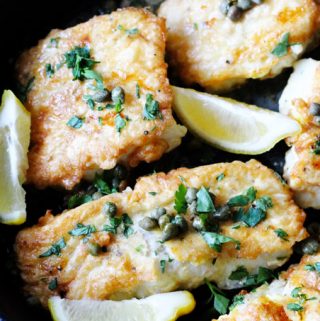 Pan fried fish with butter lemon sauce in a skillet