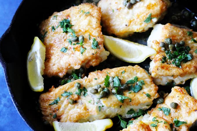 Pan fried fish with butter lemon sauce in a skillet
