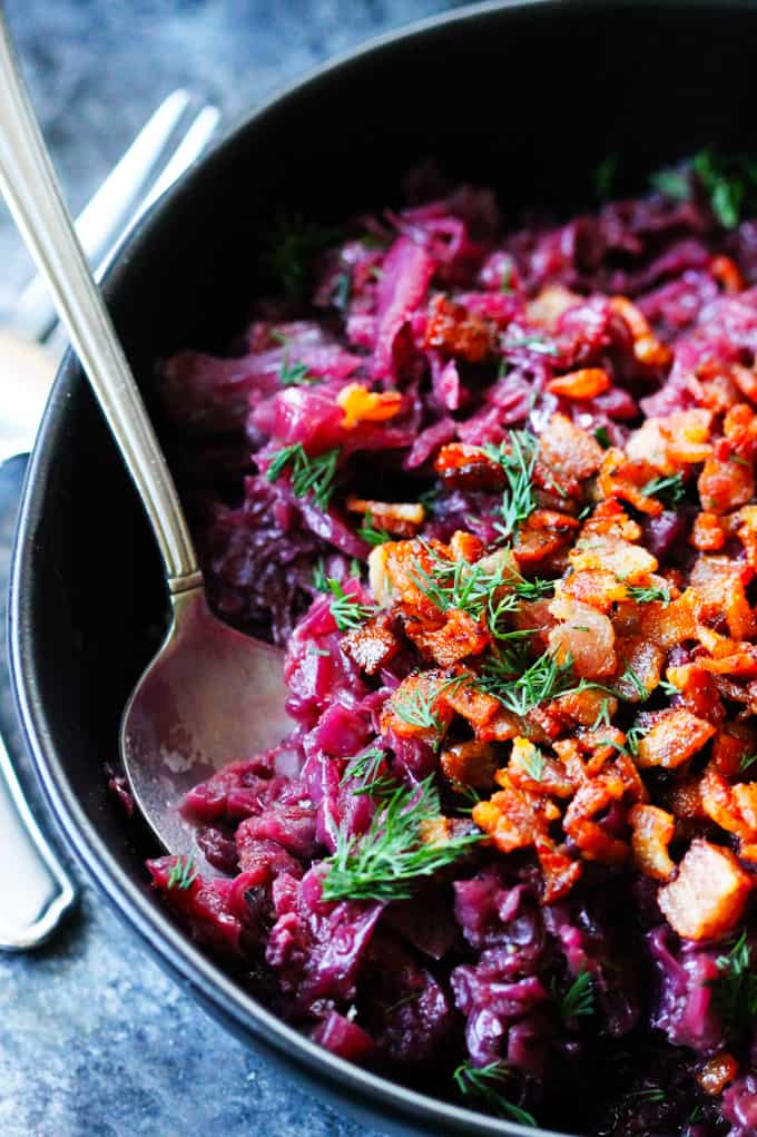 Red braised cabbage with bacon bits in a bowl with spoon.