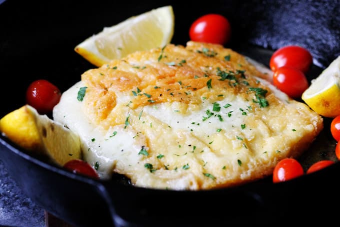 Greek Fried Cheese Saganaki in a skillet with lemon wedges