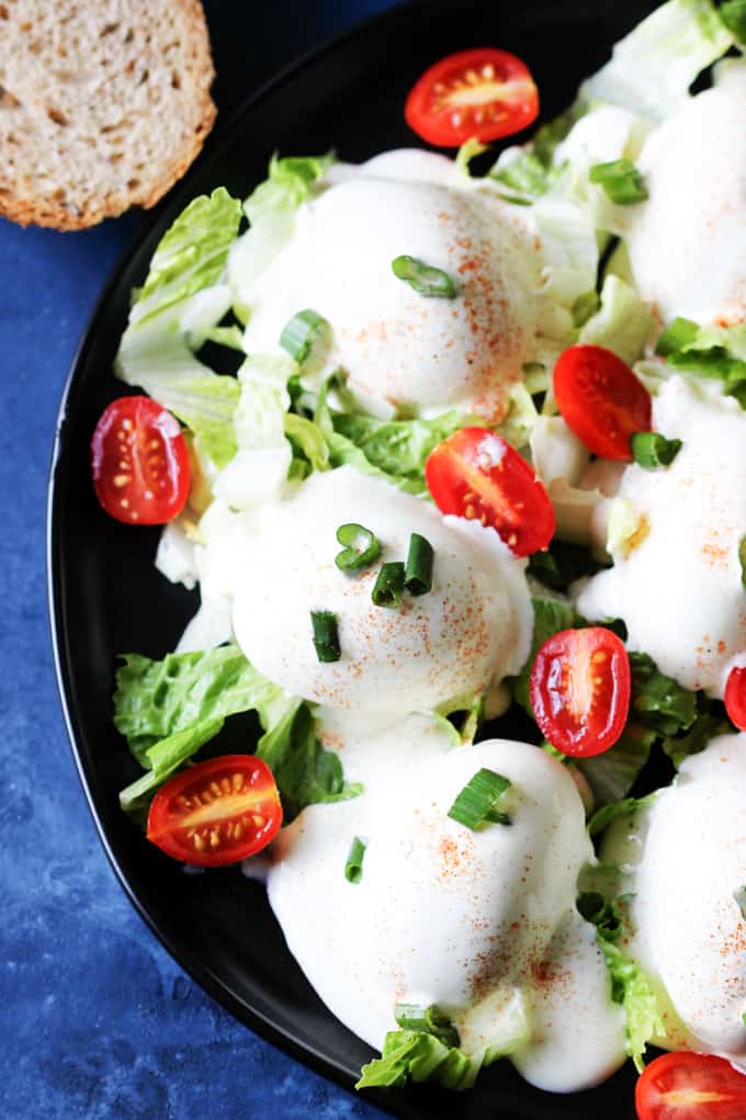 Eggs Mayonnaise on a black plate with bread behind