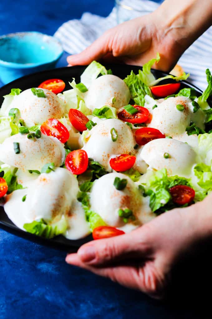 Serving Eggs Mayonnaise on a black serving plate with scallions and cherry tomatoes