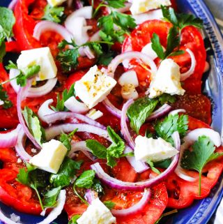 Tomato Feta Salad with herbs on a blue serving plate