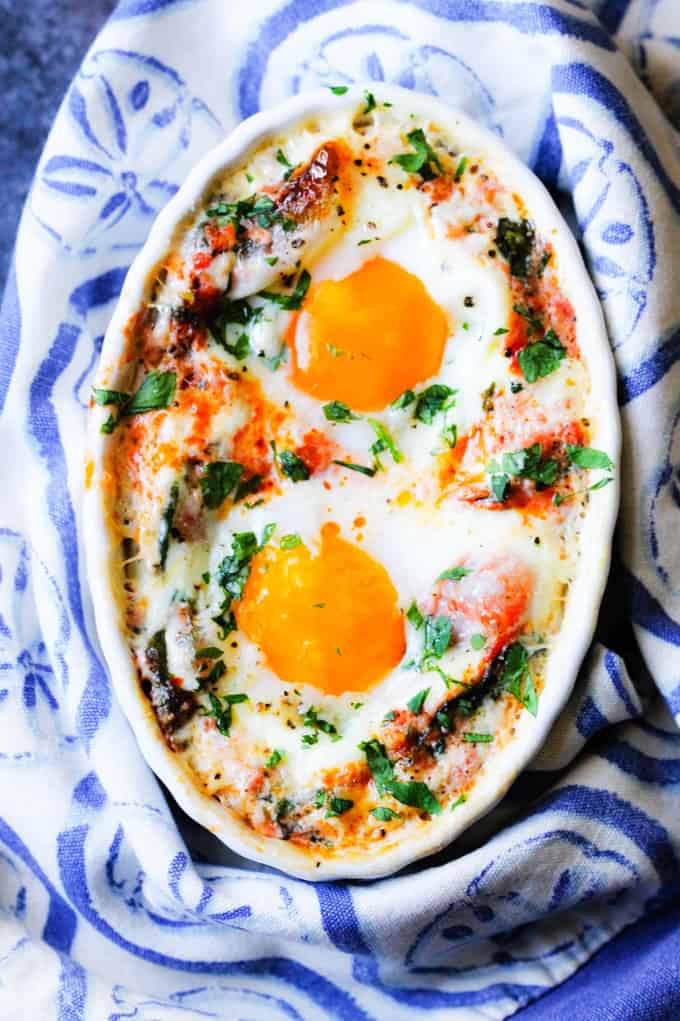 Baked eggs in tomato cream spinach sauce with kitchen towel