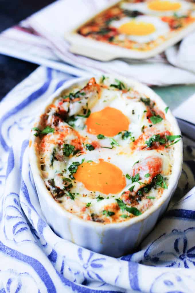 Baked eggs in ramekin with cookbook in the back