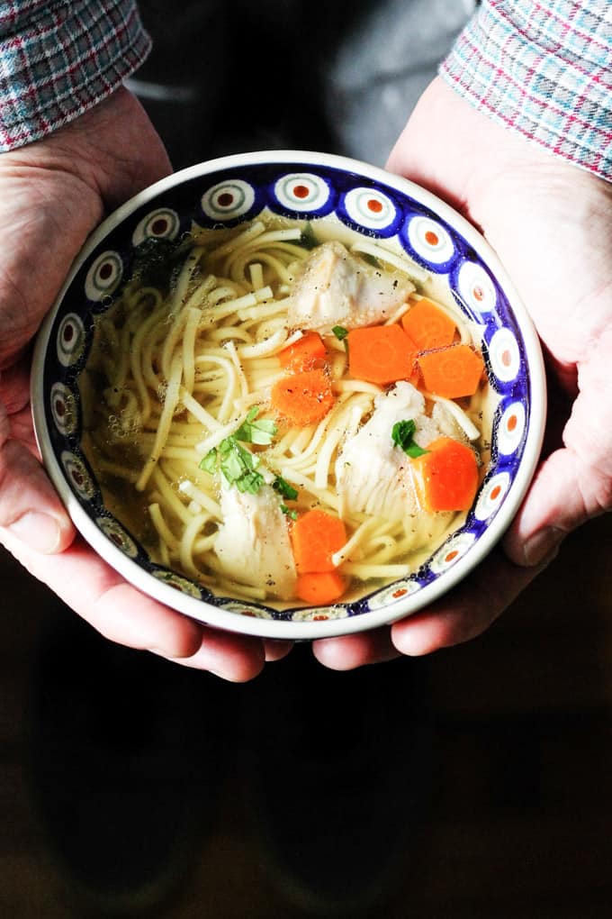 Hands holding a bowl of Rosol Polish Chicken Soup