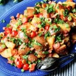 Horizontal photo of Spanish Potato Salad with Smoked Paprika Dressing on a blue serving plate with spoon