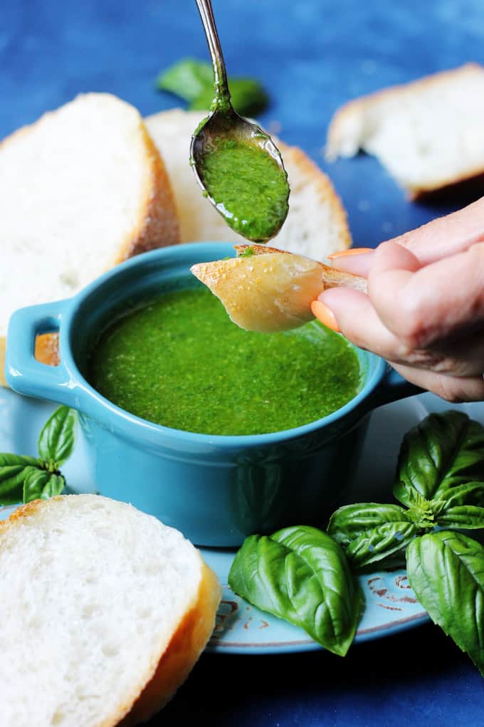 Spooning basil sauce on a piece of bread