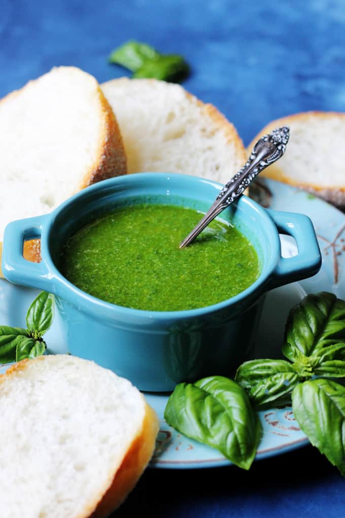 Garlic basil sauce in a ramekin with bread ion a side