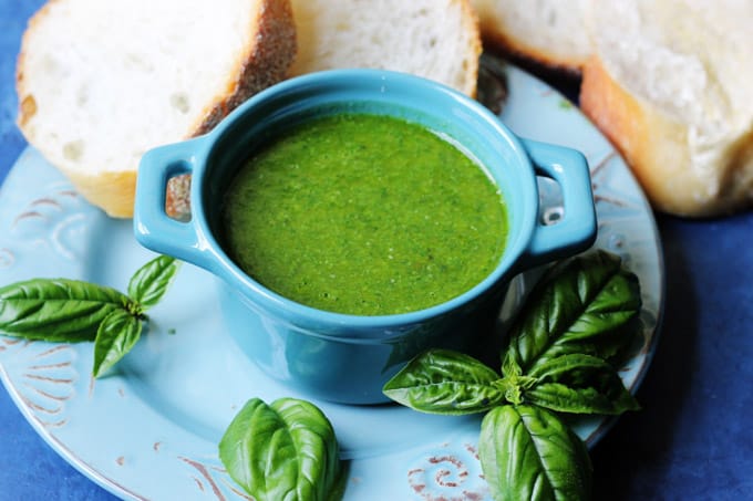 Horizontal shot of basil sauce in blue ramekin and bread on a side