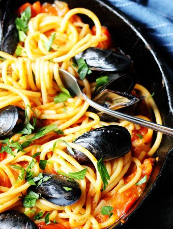 Pasta with Mussels in spicy tomato sauce in a cast iron skillet with the fork