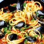 Horizontal photo of pasta with mussels and spicy tomato sauce in a skillet