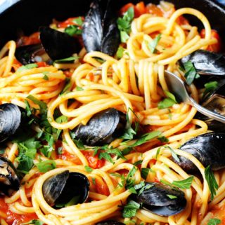 Horizontal photo of pasta with mussels and spicy tomato sauce in a skillet