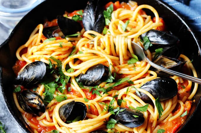 Horizontal photo of pasta with mussels and spicy tomato sauce in a skillet