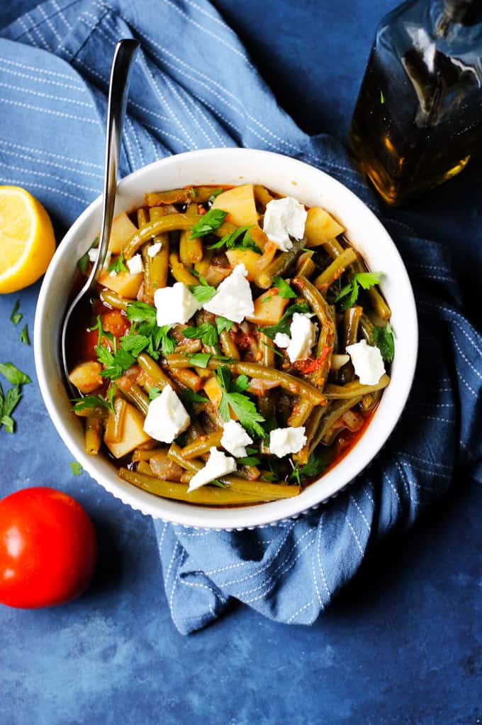 Greek Fasolakia in a bowl with spoon on a blue kitchen towel