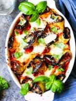 Eggplant Rollatini Parmigiana in a casserole dish with towel on a side