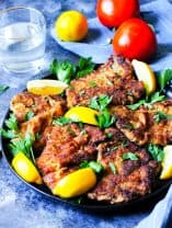 Veal Milanese on a plate with lemon wedges
