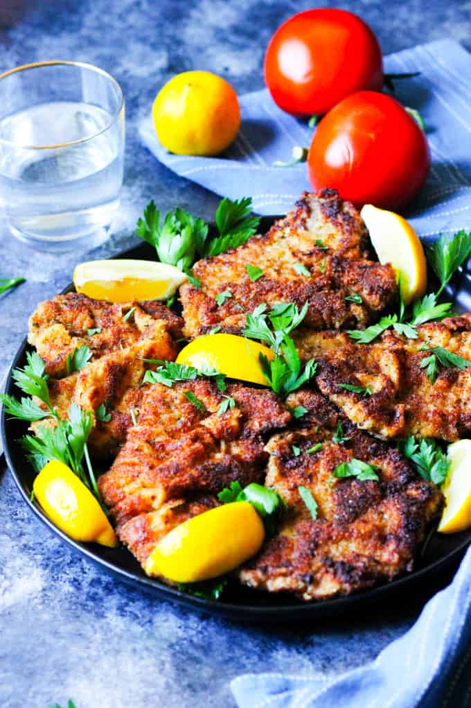 Veal Milanese on a plate with lemon wedges