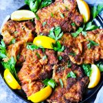 Italian breaded veal cutlets on a plate with blue background