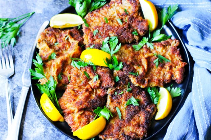 Italian breaded veal cutlets on a plate with blue background