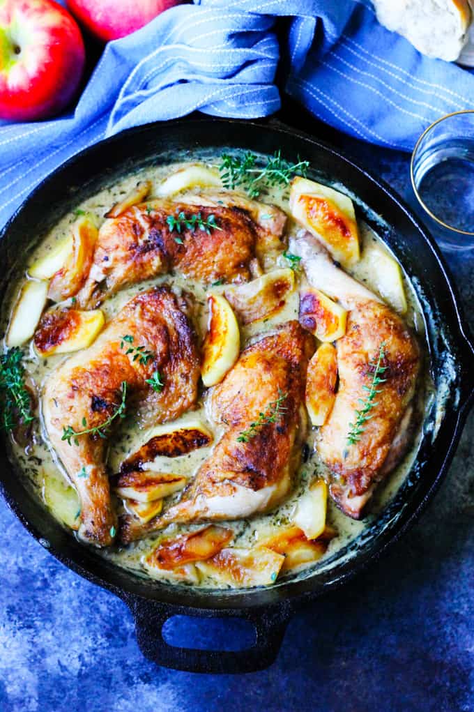 Chicken Normandy braised in apple cider and cream in a skillet with apples