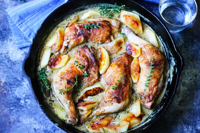 Chicken Normandy in a skillet with blue background