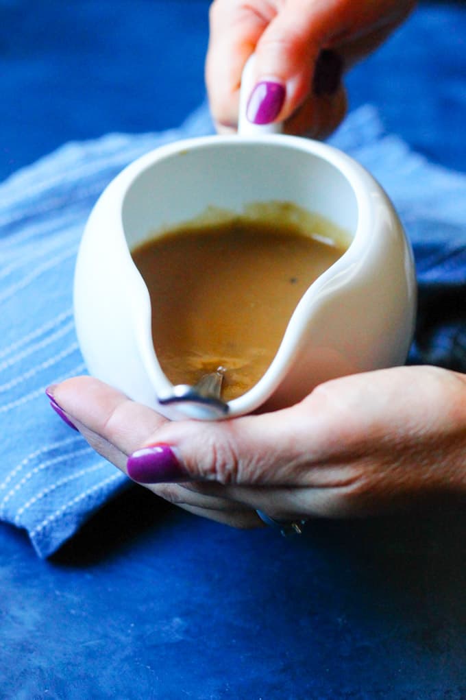 Hands holding easy homemade gravy in serving dish with spoon