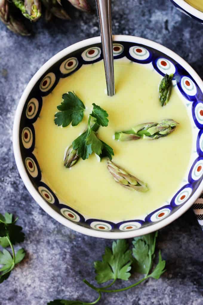 Green creamy asparagus soup in a bowl with a spoon