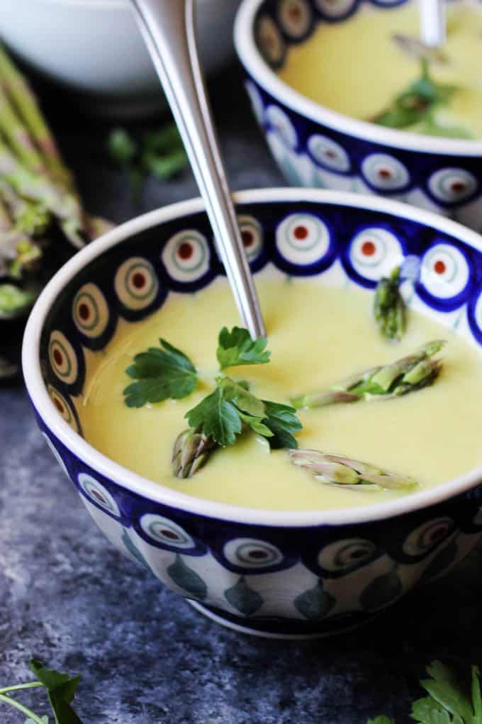 Two bowls of creamy green asparagus soup