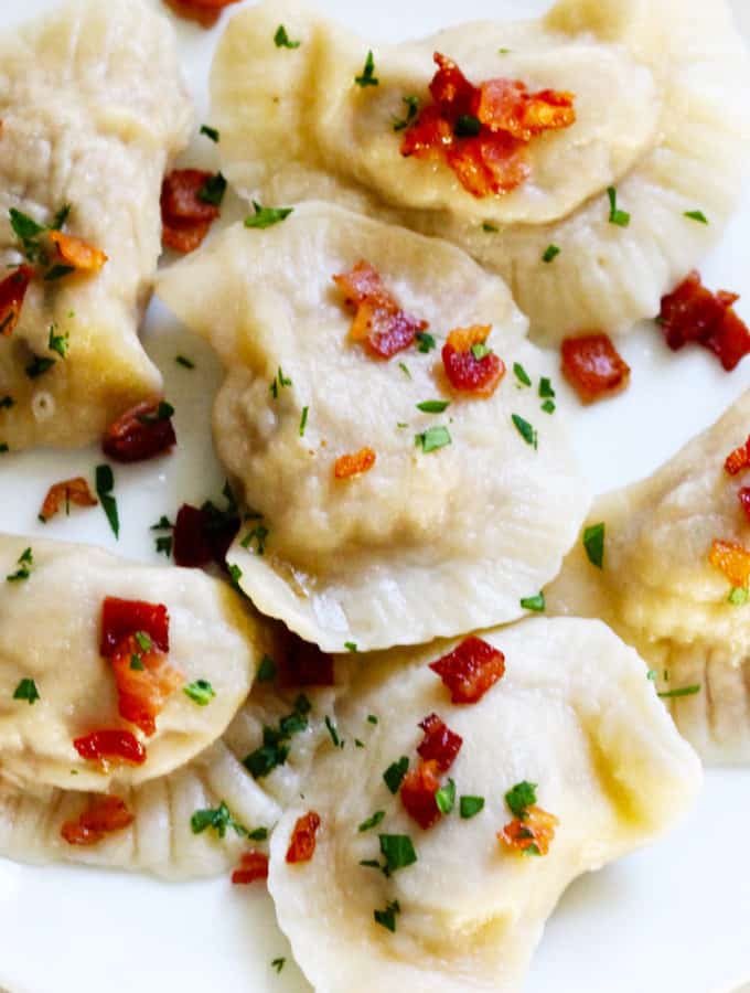 Polish Meat Pierogi on a white plate with bacon bits
