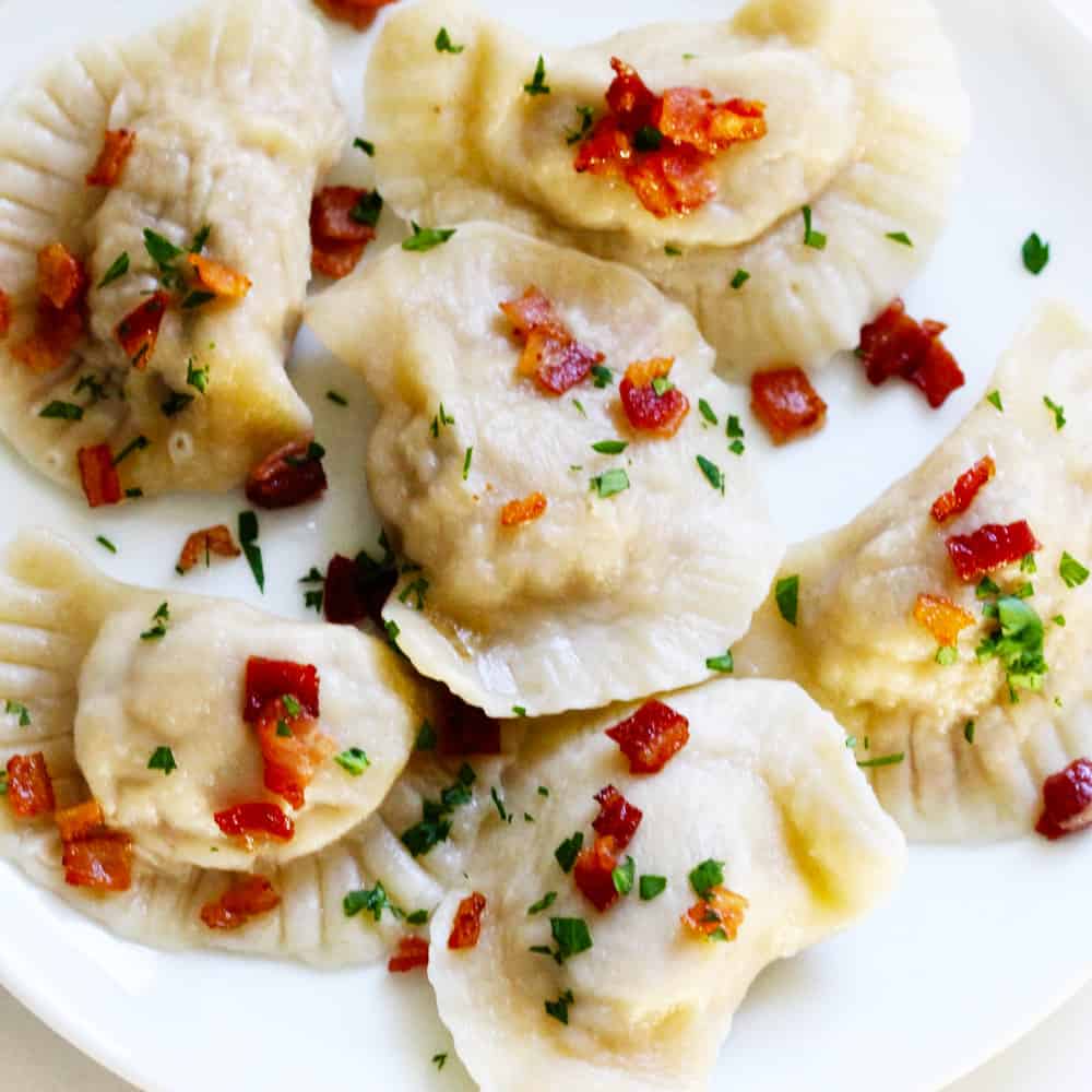 Polish Meat Pierogi on a white plate with bacon bits