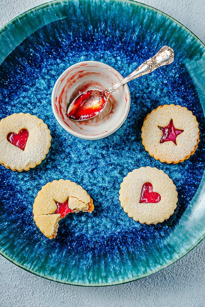 Picture of Linzer Cookies on a blue plate with empty jam bowl